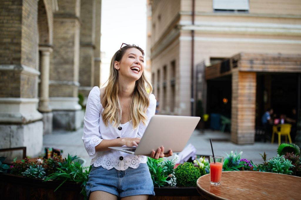 Happy excited woman reading good news on line in a laptop outdoor