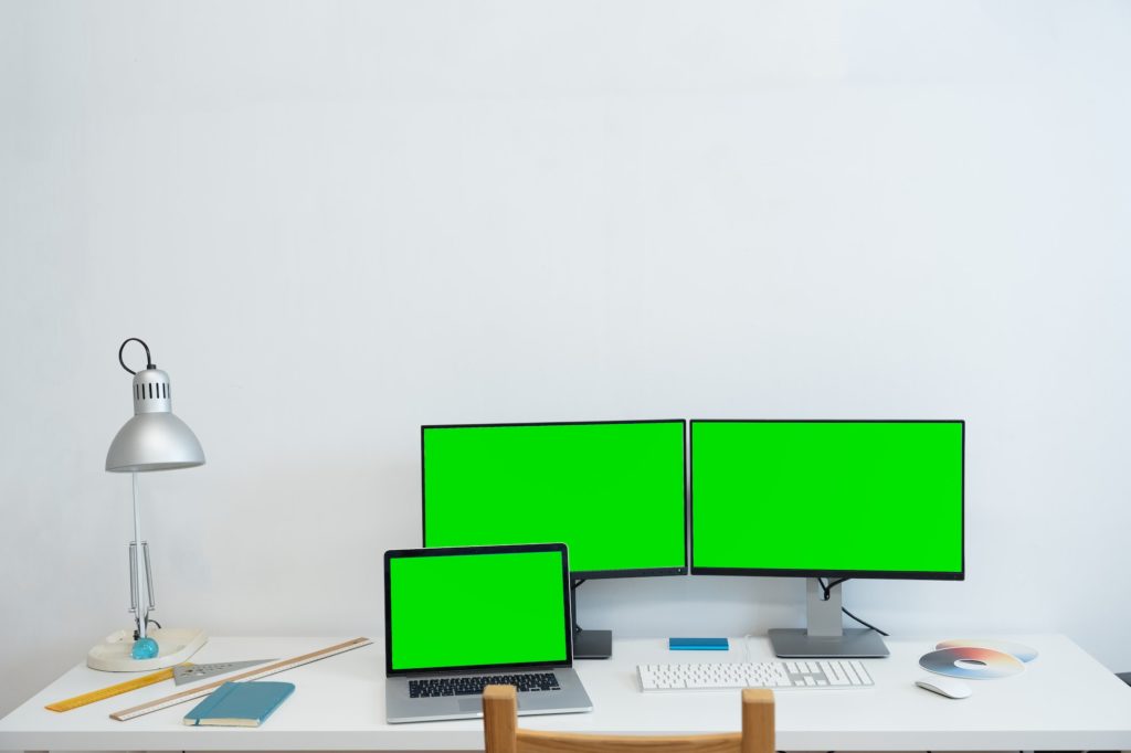 Green screen monitor stands on the office desk - Personal compute mock-up.
