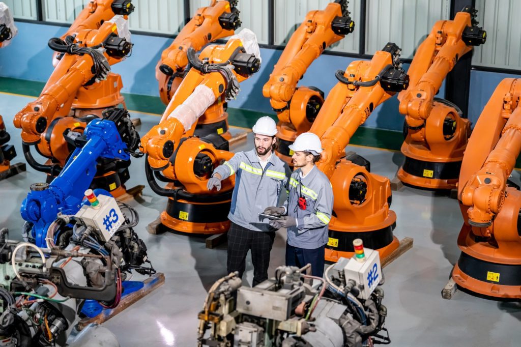 Engineer inspecting automatic AI robot arm and machines in factory. Engineer inspecting automatic AI