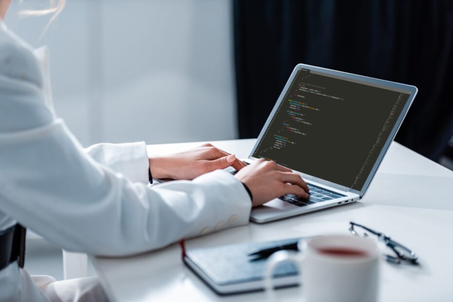 cropped view of woman using laptop with microsoft windows on screen at office desk
