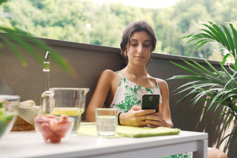 Woman sitting on the balcony and using her smartphone