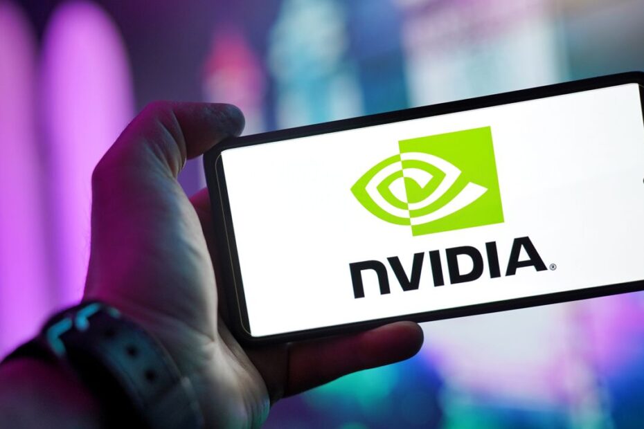 Close-up of a hand holding a smartphone showing the NVIDIA logo on screen with a blurred background.